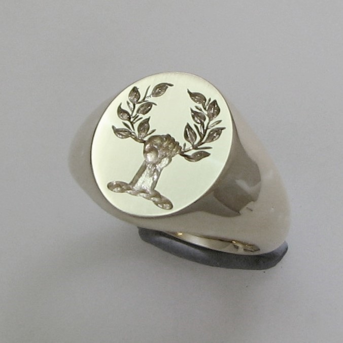 Hand holding wreath crest engraved signet ring